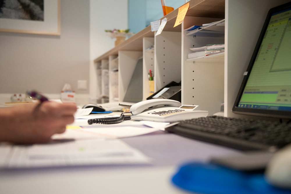Patienten-Empfang mit Sicht auf den Arbeitsplatz mit Telefonen und Bildschirmen