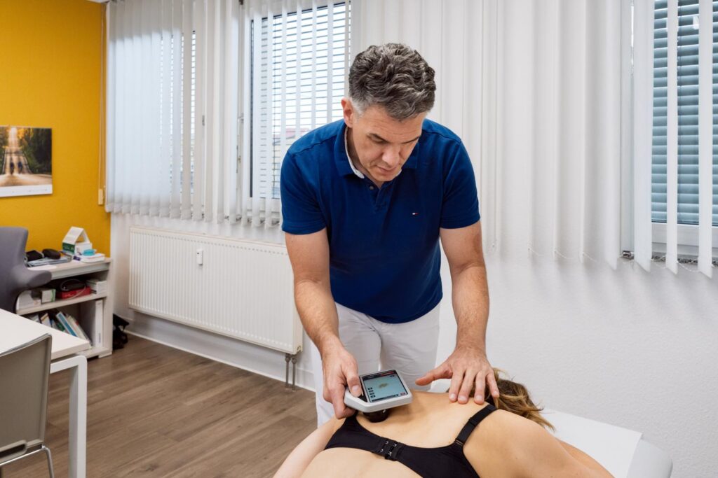 Dr. Dimos beim digitalen Hautcheck an einer liegenden Patientin